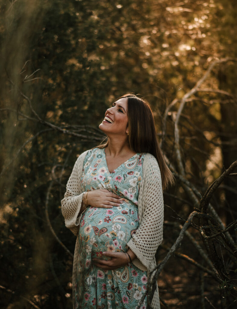 Fotografía de embarazo en Navarra, mujer embarazada sonriendo en la naturaleza durante una sesión familiar de Pía Alvero.