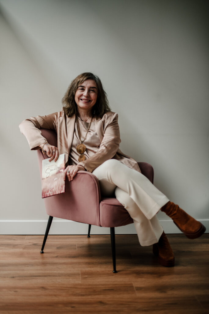 Retrato profesional de psicóloga sentada en sofá rosa, fotografiada por Pía Alvero en una sesión de marca personal. Psicologa Cristina Cortes