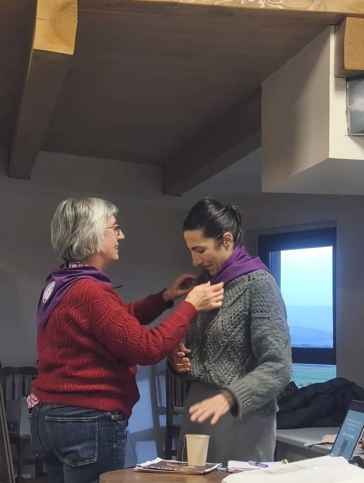 Participante colocando un pañuelo morado a otra mujer durante un taller participativo de igualdad de Pía Alvero.